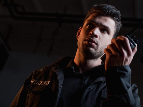 guard-in-uniform-using-walkie-talkie-and-looking